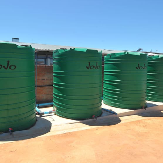 Four green JoJo water tanks on a concrete base