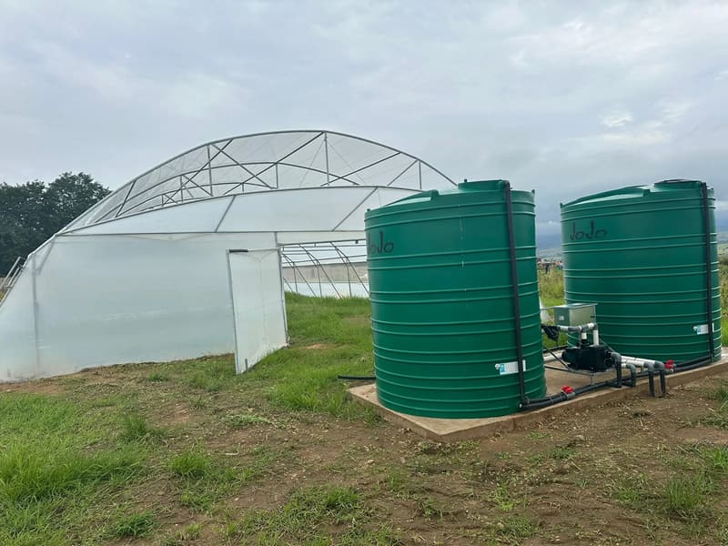 A tunnel with two green water tanks and a pump beside it