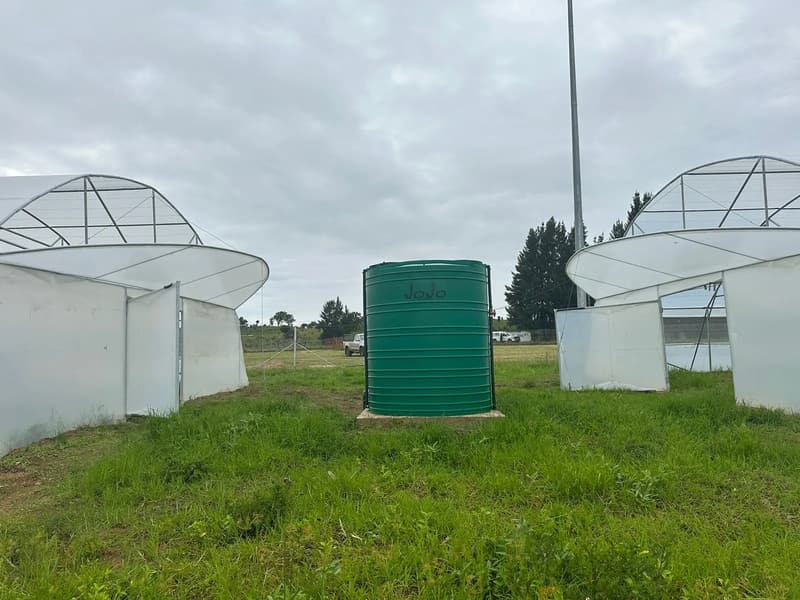 Green JoJo tank on a concrete base between two tunnels with raised end flaps